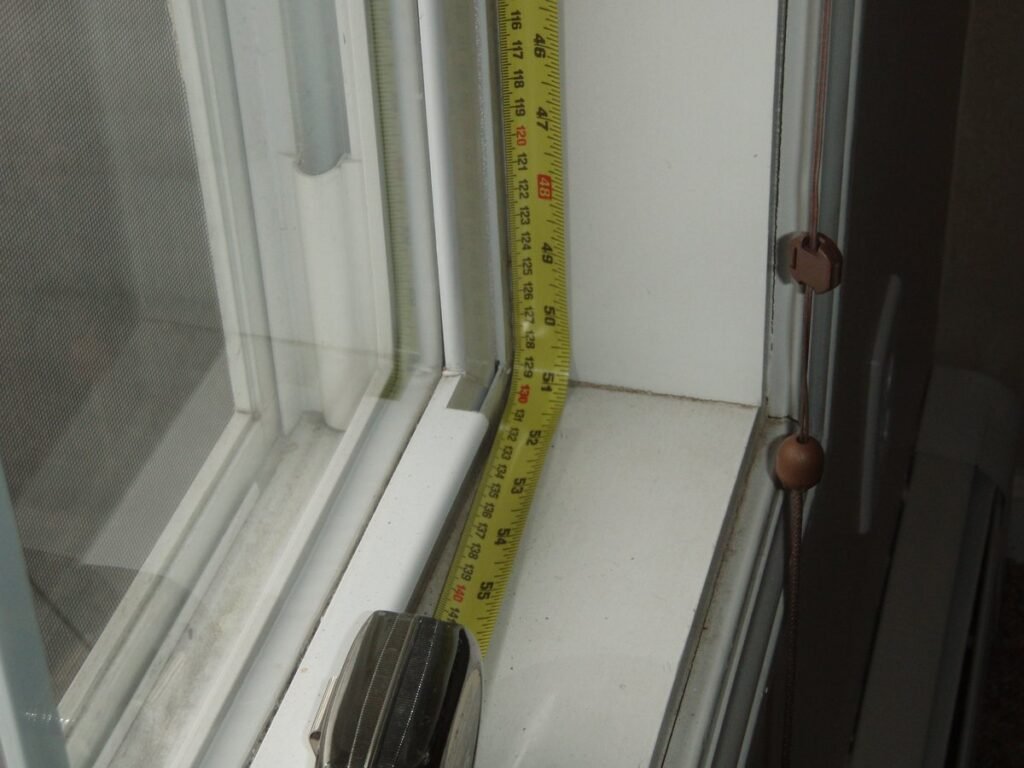 Midiendo con una cinta métrica la holgura del marco de una ventana